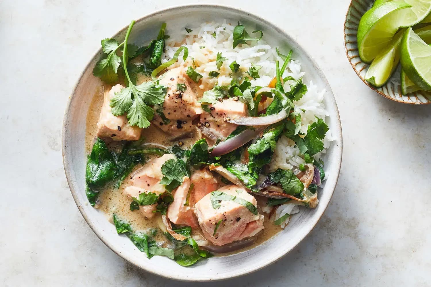 Bowl of coconut miso salmon with a side of lime wedges